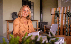 Francis van De Heldenreis zit aan tafel met een boek en laptop en ondersteunt gezinnen bij emigreren met kinderen.