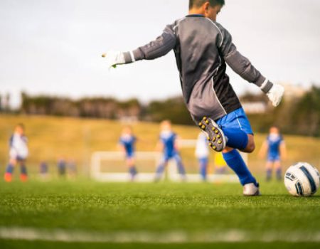 Little soccer player in soccer field playing soccer outdoor in casual clothing.